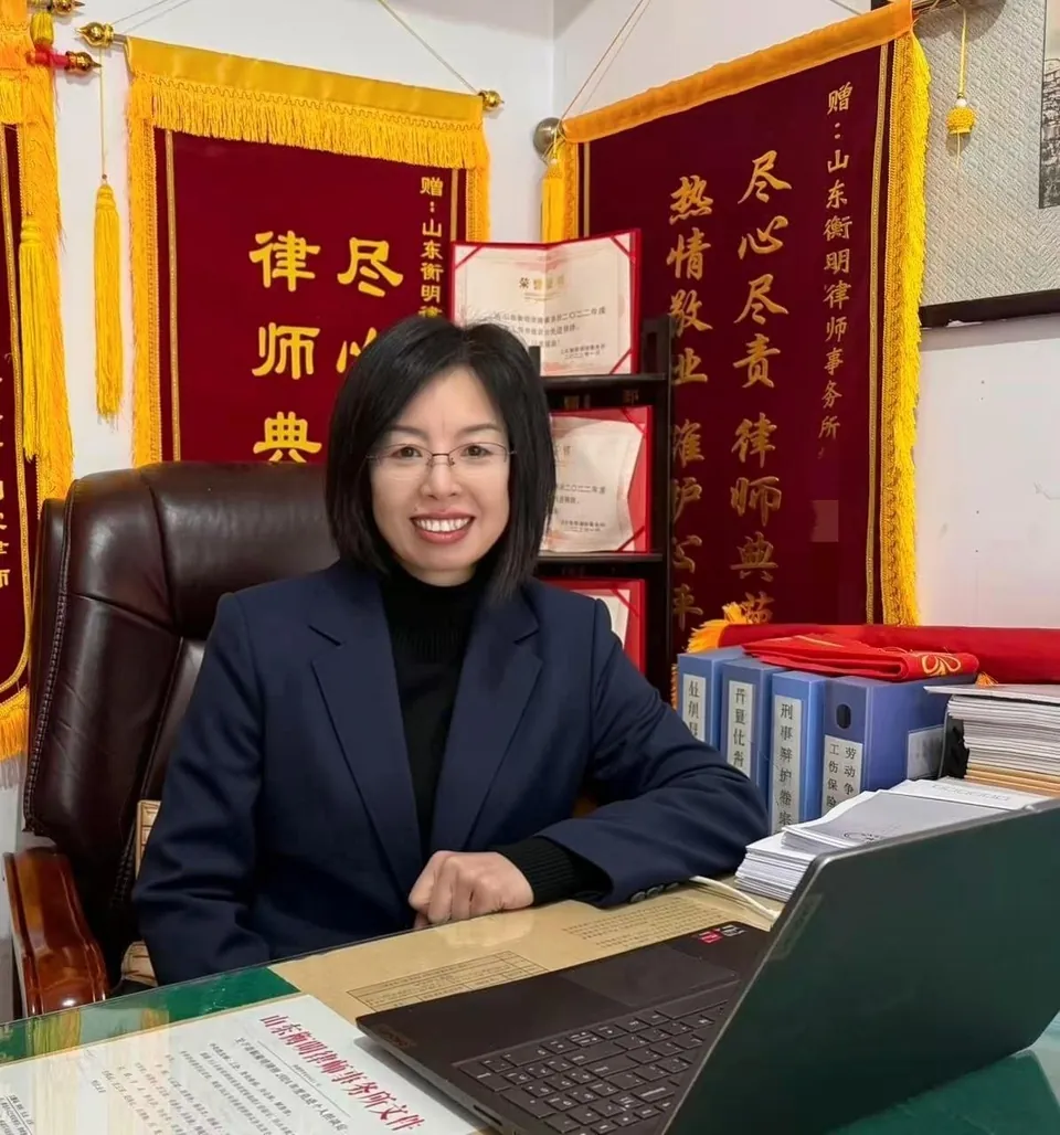 刘霞律师在办公室,背景为当事人赠送的锦旗与荣誉证书